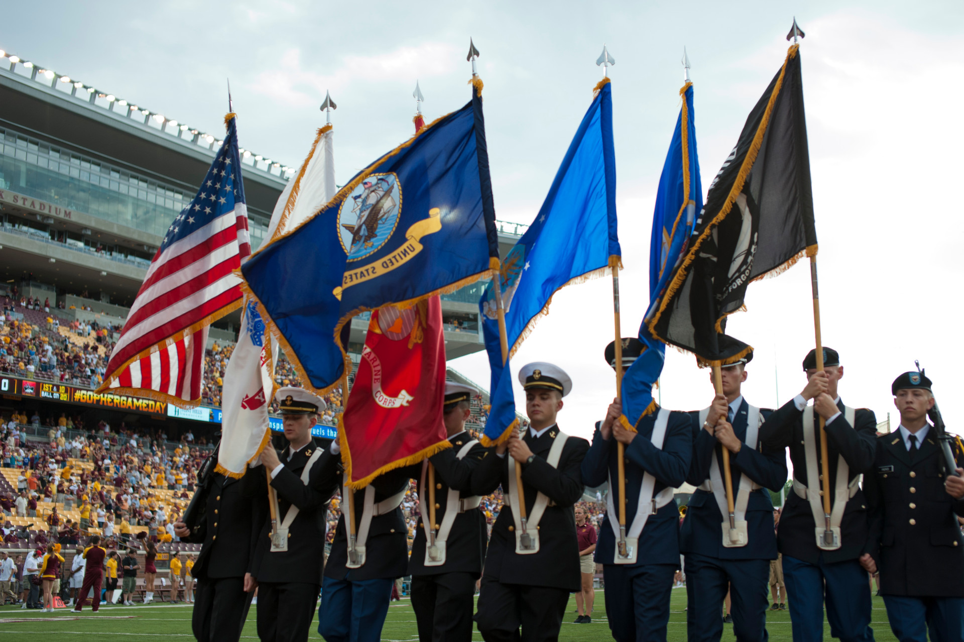 Members of the University of Minnesota ROTC carry the nation and state flags at a football game