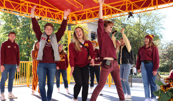 Student tour guides singing and dancing at an outdoor event
