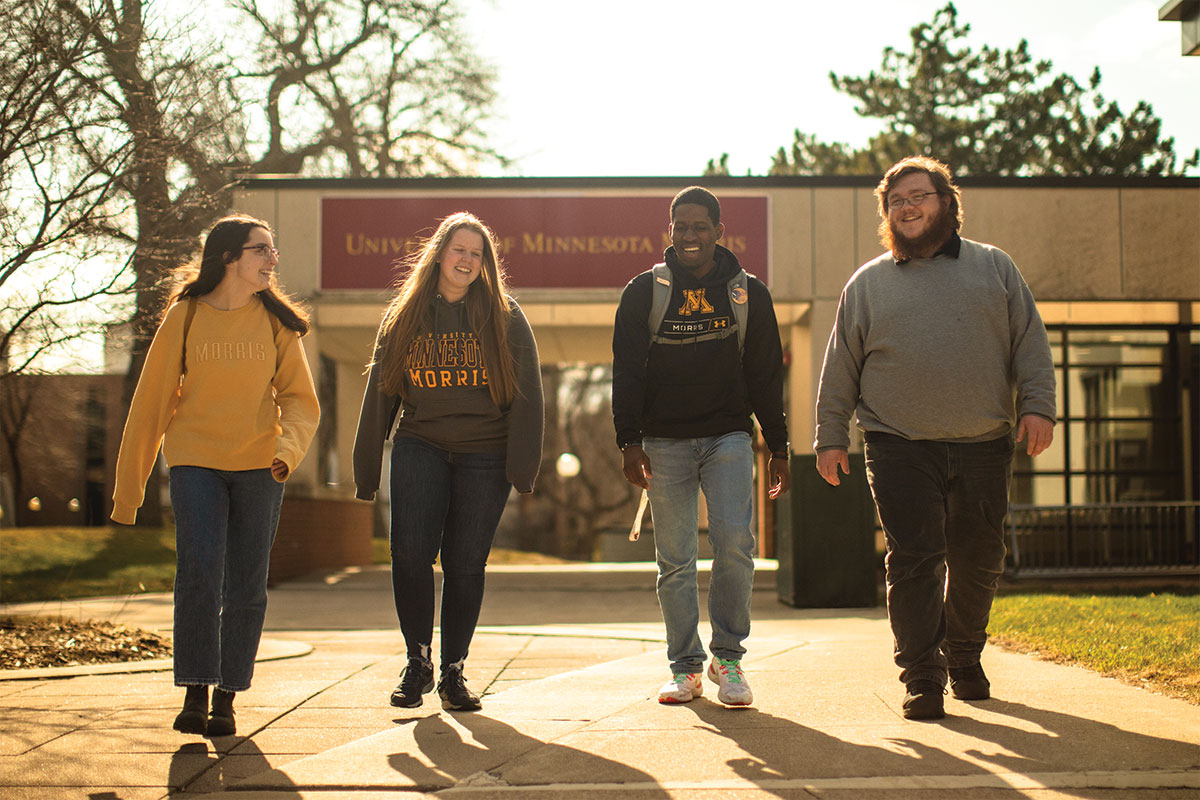Four students talking together, walking out of a campus building