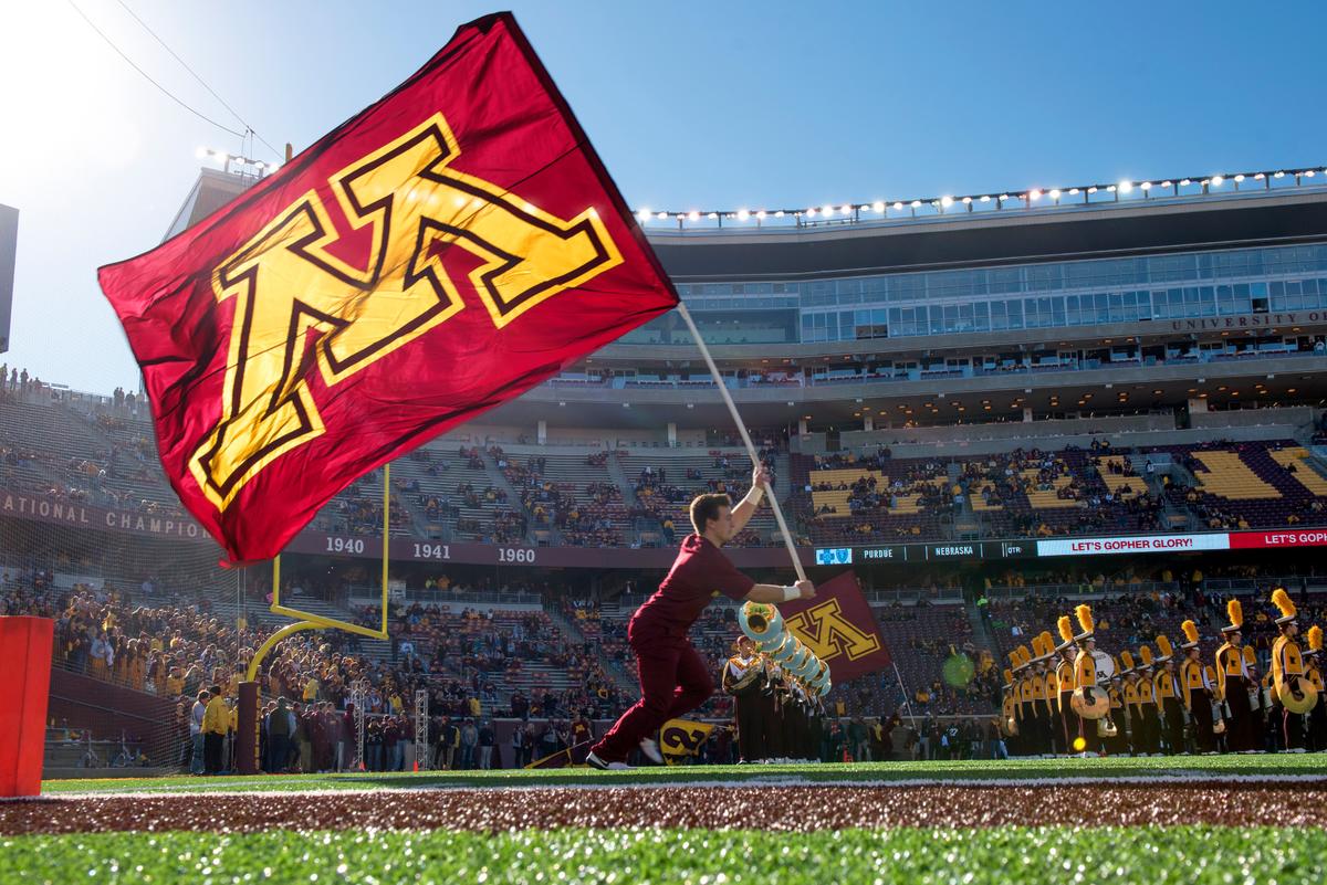 A member of the Spirit Squad runs on the field with a giant Maroon Block M flag