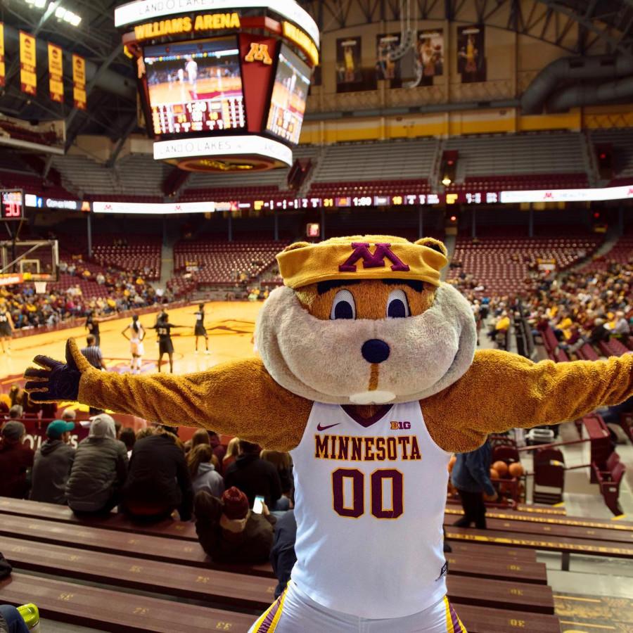 Goldy Gopher mascot with outstretched arms in front of basketball court at Williams Arena