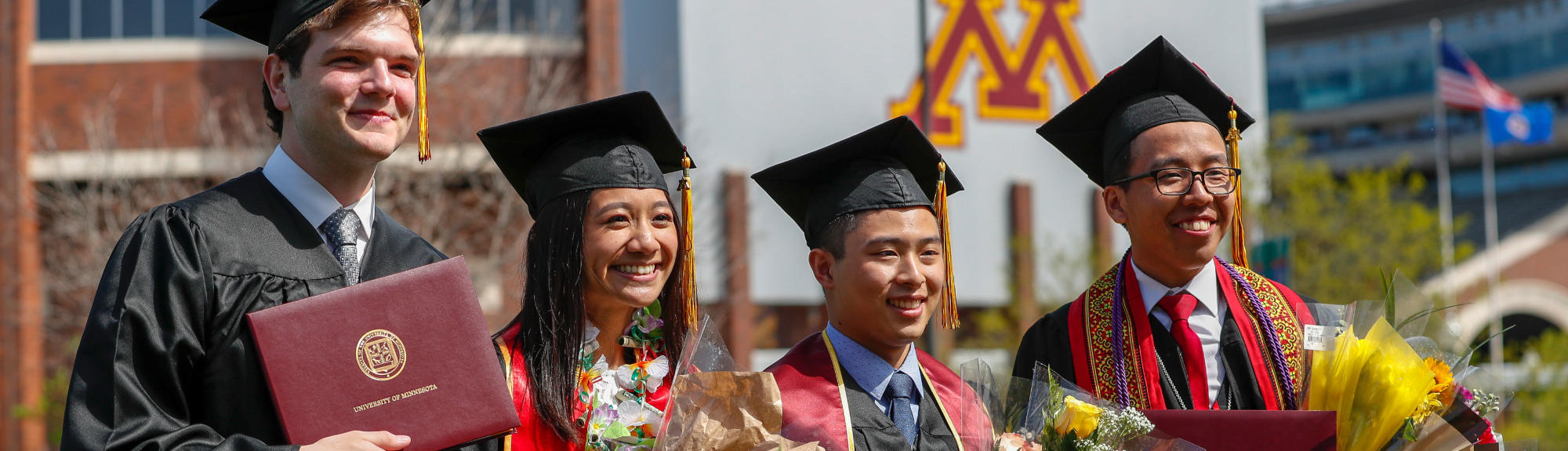 Graduates stand with their deplomas outside TCF Bank Stadium