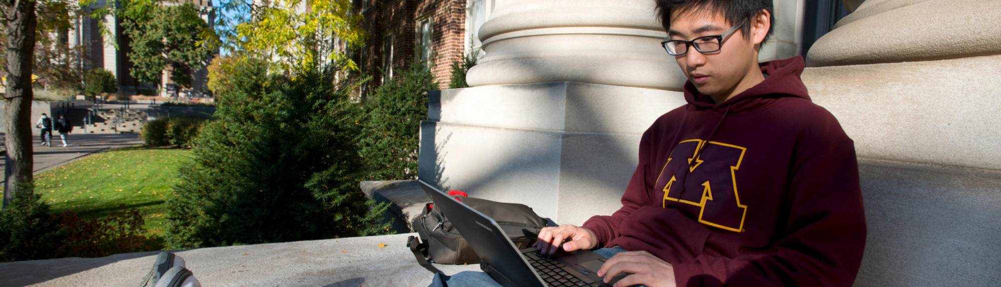 A student works outside on their laptop